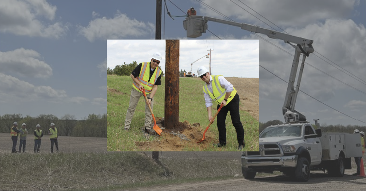 Two men dig by an electrical pole.