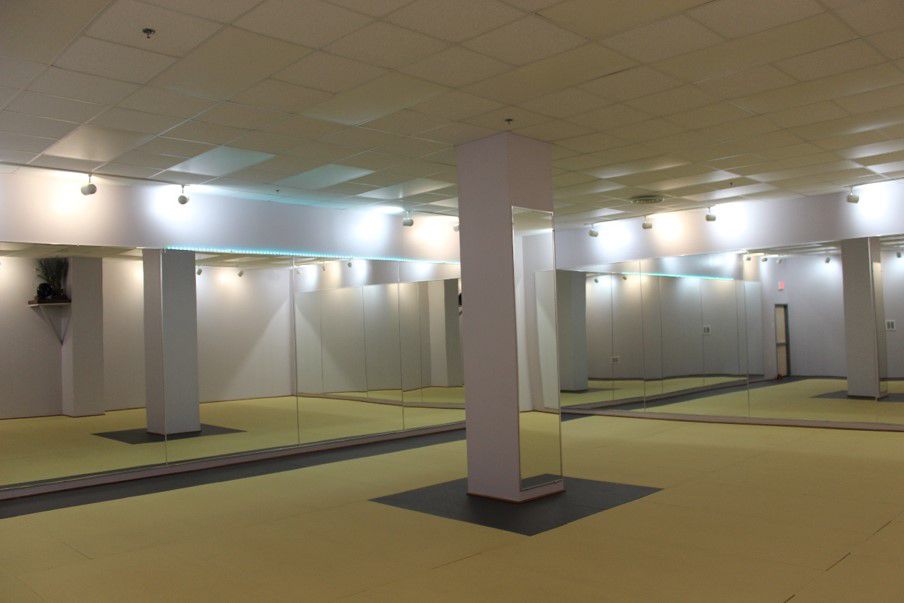 Empty hot yoga studio with mirrored walls, white columns and a drop ceiling
