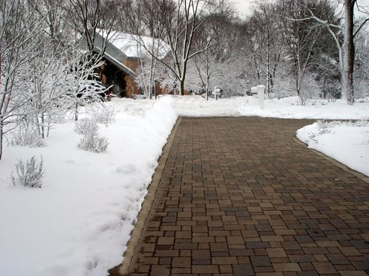 Clear paver driveway through a snowy yard