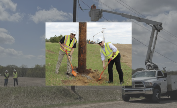 Two men dig by an electrical pole.